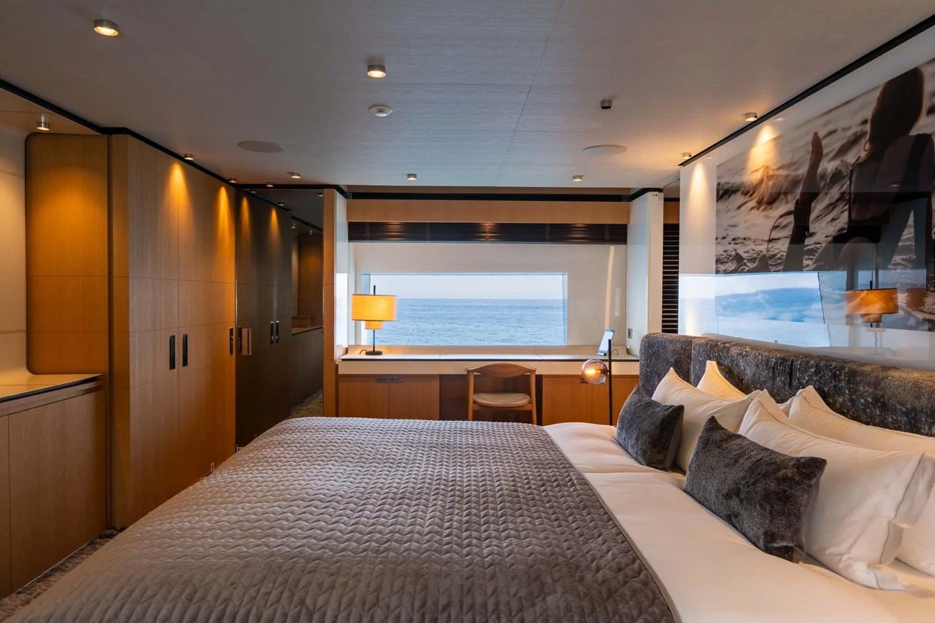 The master stateroom features a luxurious bed with a view of the sea through a large window. aboard MR. T Yacht for Sale
