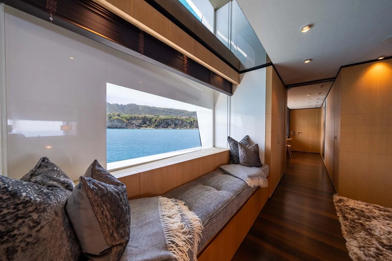 A cozy lounge area with a large window offering a scenic view of the water. aboard MR. T Yacht for Sale
