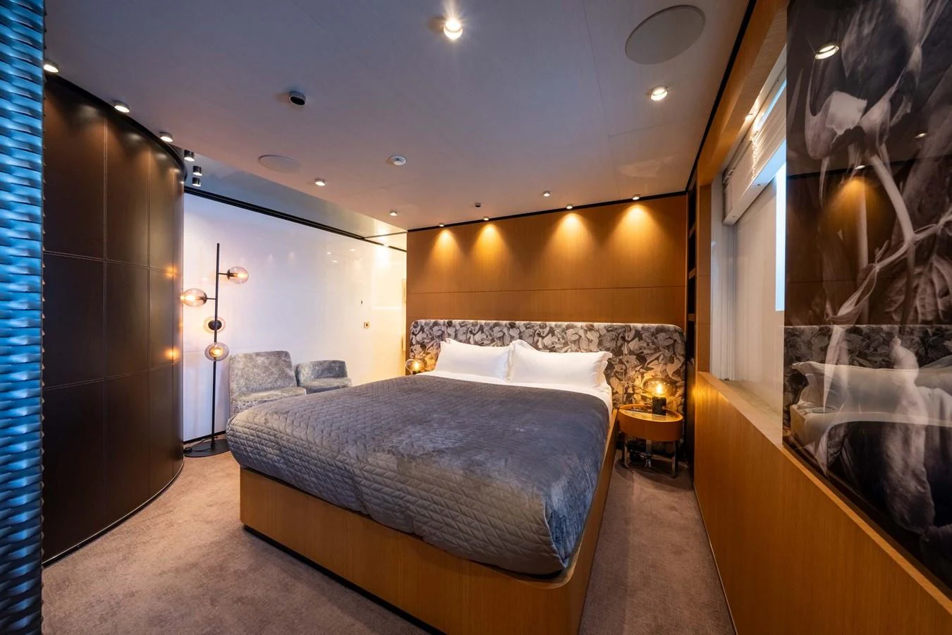 The stateroom features a luxurious bed with elegant lighting and modern decor. aboard MR. T Yacht for Sale