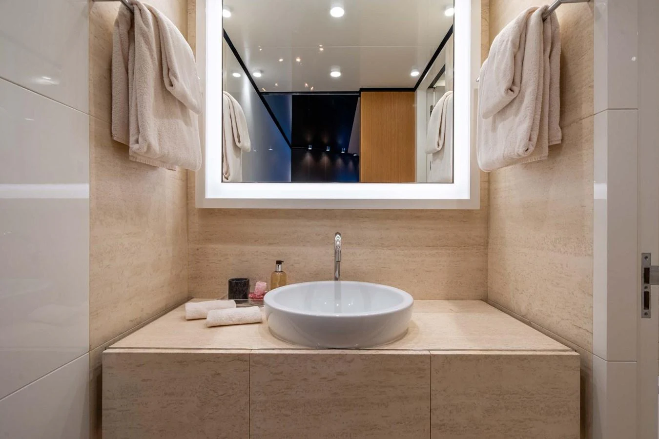 The bathroom features a modern sink with elegant lighting and plush towels. aboard MR. T Yacht for Sale