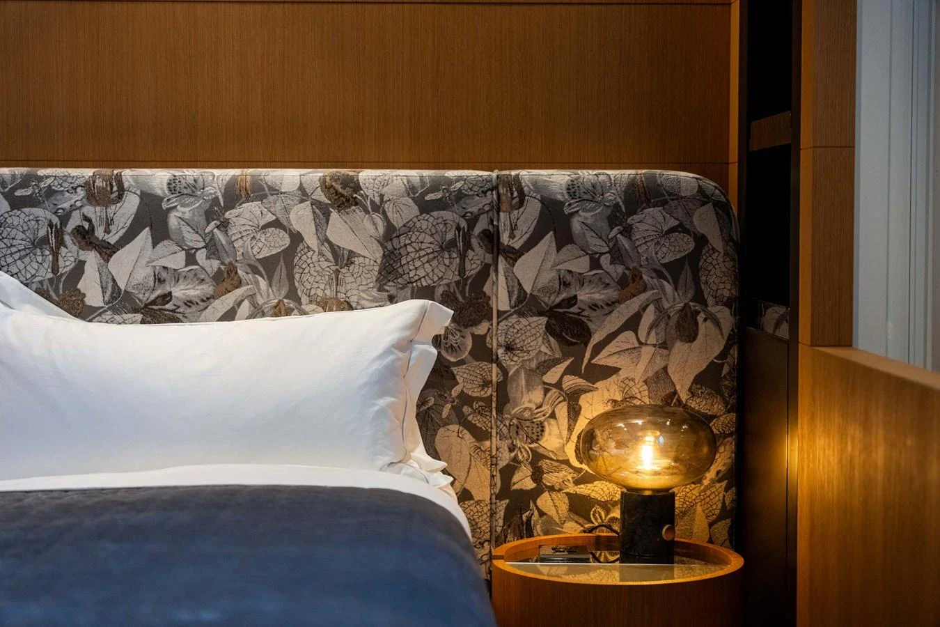 A cozy stateroom featuring a bed with a floral-patterned headboard and a stylish bedside lamp. aboard MR. T Yacht for Sale