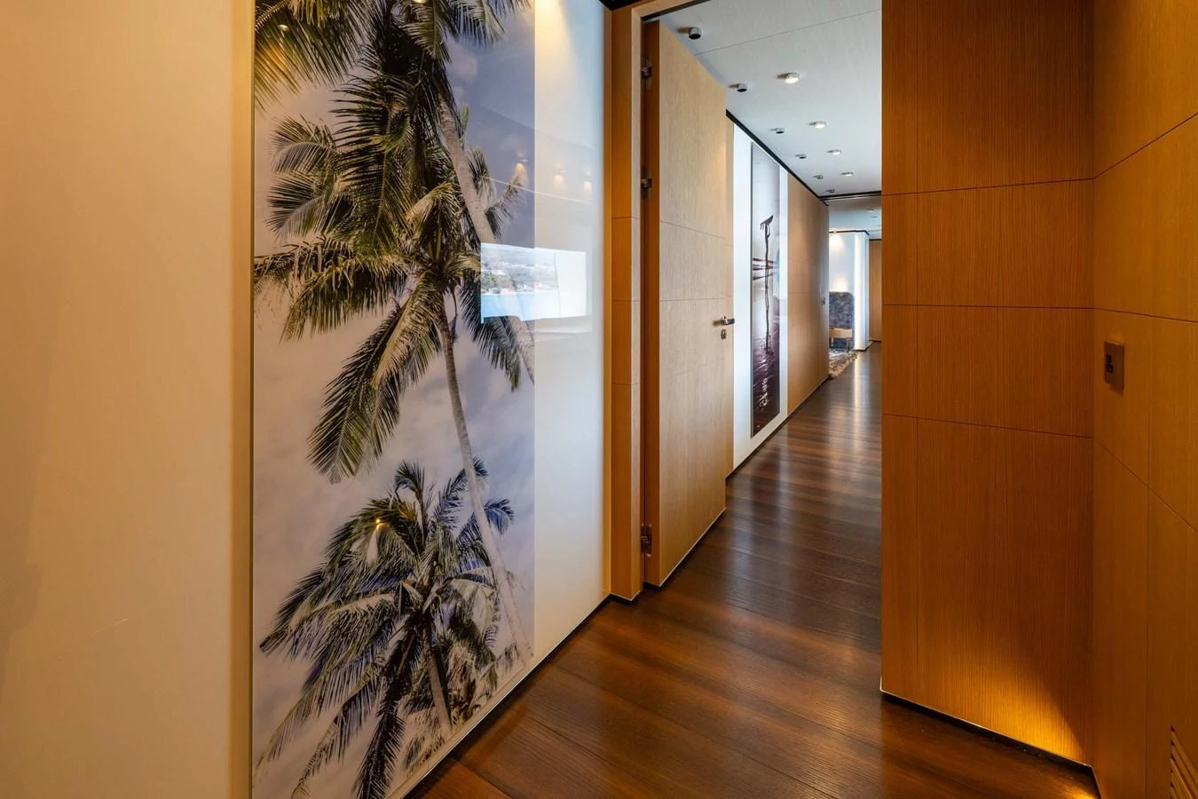 A sleek hallway with wooden flooring and a large palm tree artwork on the wall. aboard MR. T Yacht for Sale