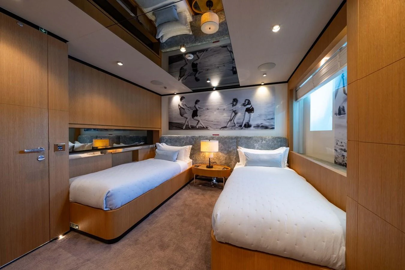 The guest stateroom features twin beds, warm wood paneling, and a stylish black-and-white photograph above the headboards. aboard MR. T Yacht for Sale