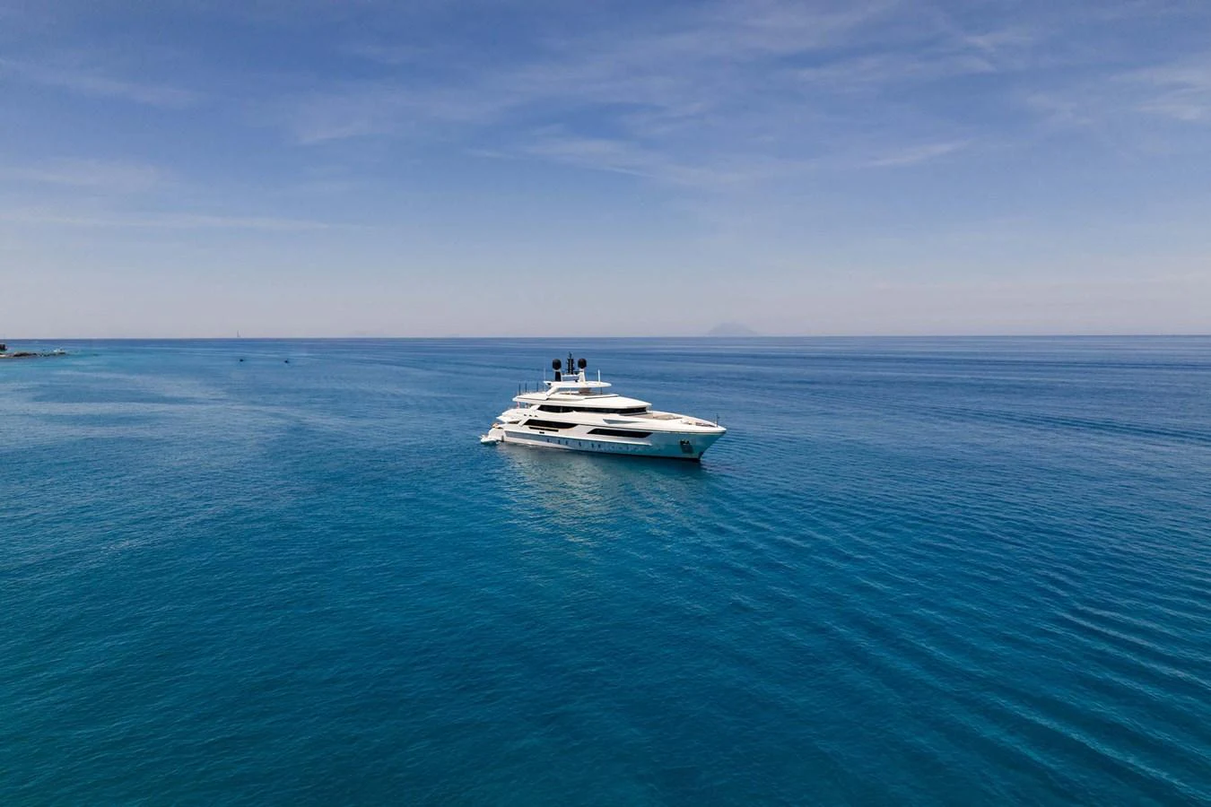 A luxurious yacht cruises through serene, clear blue waters under a vast, open sky. aboard MR. T Yacht for Sale