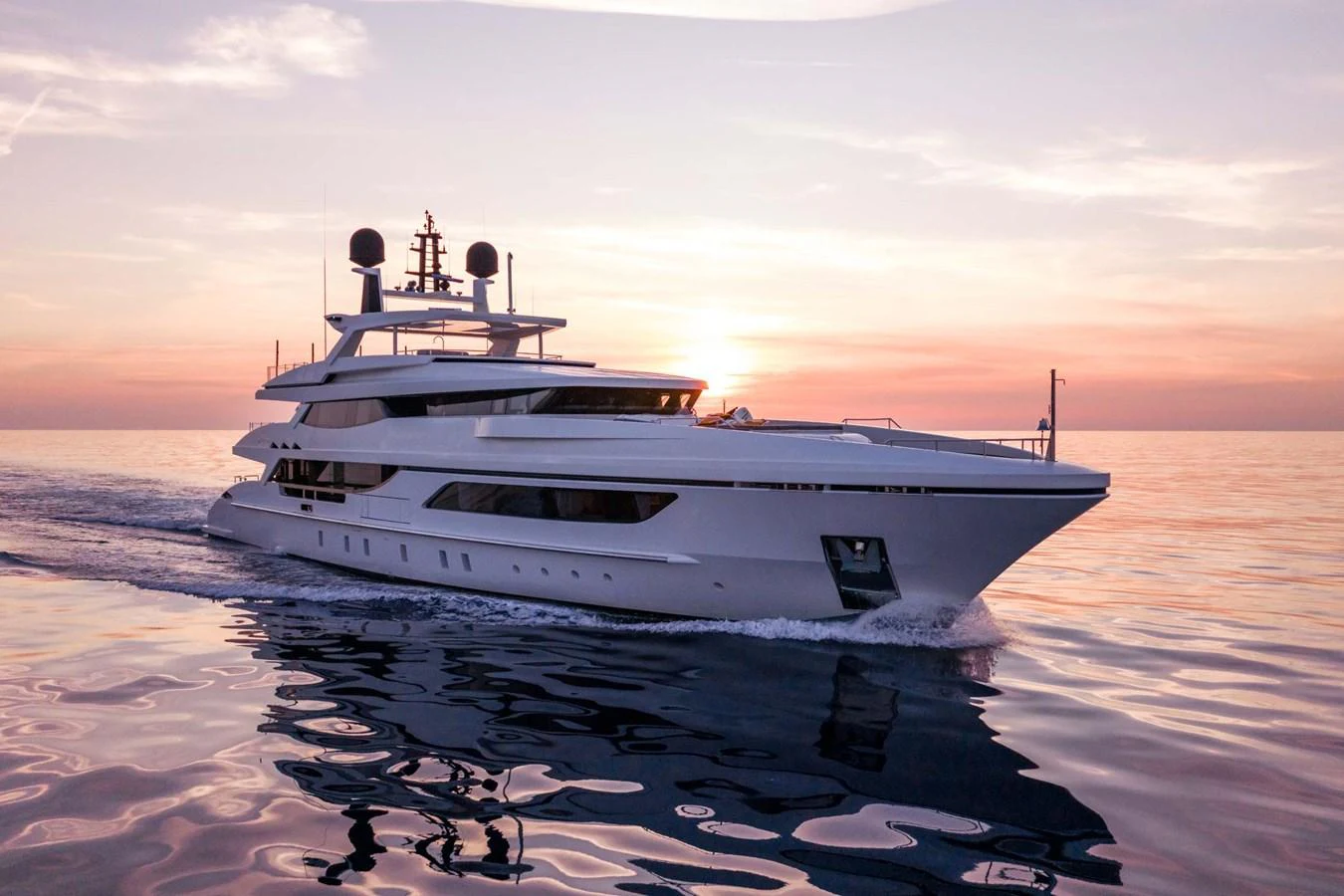 A sleek and modern yacht glides gracefully on calm waters during a stunning sunset. aboard MR. T Yacht for Sale