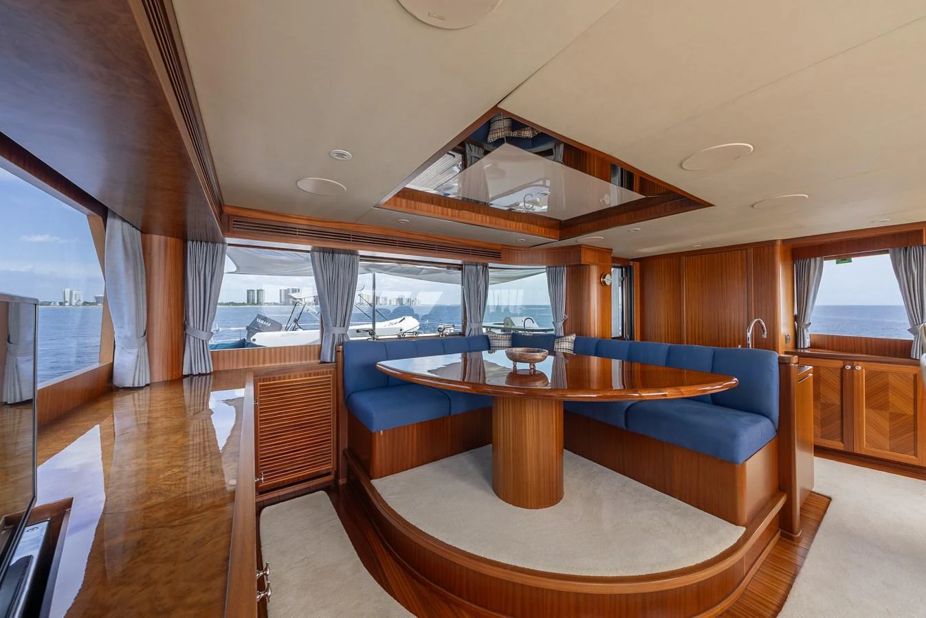 The saloon features a spacious seating area with rich wood finishes and large windows offering panoramic views. aboard ABOAT TIME Yacht for Sale