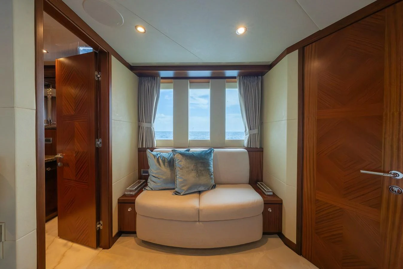 A cozy seating area with elegant wooden finishes and a view of the sea through large windows. aboard ABOAT TIME Yacht for Sale