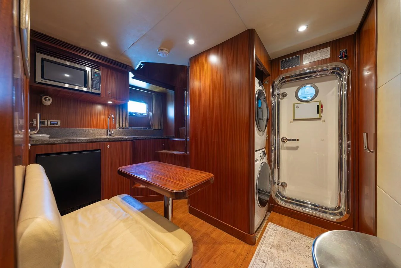 The yacht's galley features warm wood finishes, modern appliances, and a cozy dining area. aboard ABOAT TIME Yacht for Sale