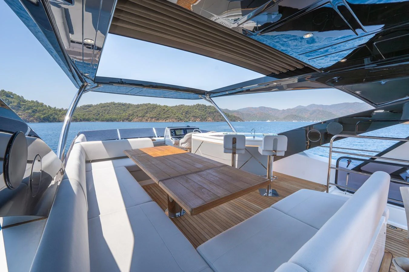 The flybridge offers a spacious seating area with a wooden table, perfect for alfresco dining with stunning sea views. aboard NAAMA Yacht for Sale