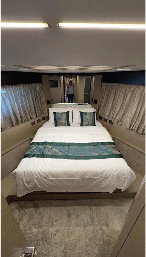 A cozy stateroom with a double bed adorned with elegant bedding and ample natural light. aboard ABIGAIL Yacht for Sale