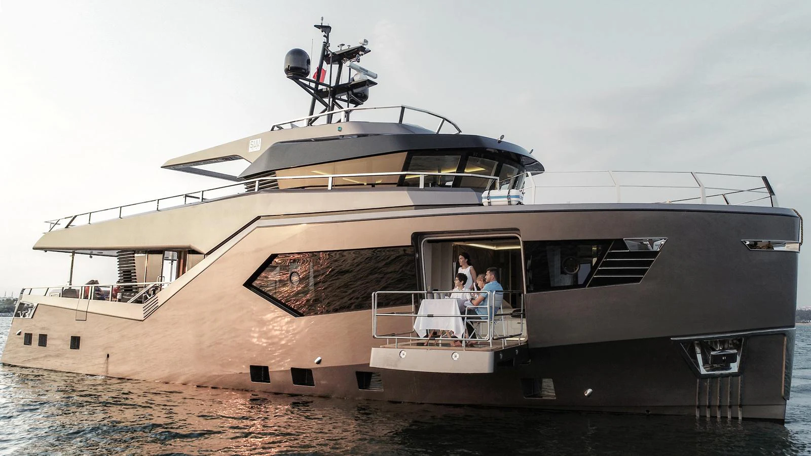 A sleek and modern yacht cruising on calm waters, featuring a stylish exterior and an intimate dining area on the deck. aboard HULL #5 Yacht for Sale