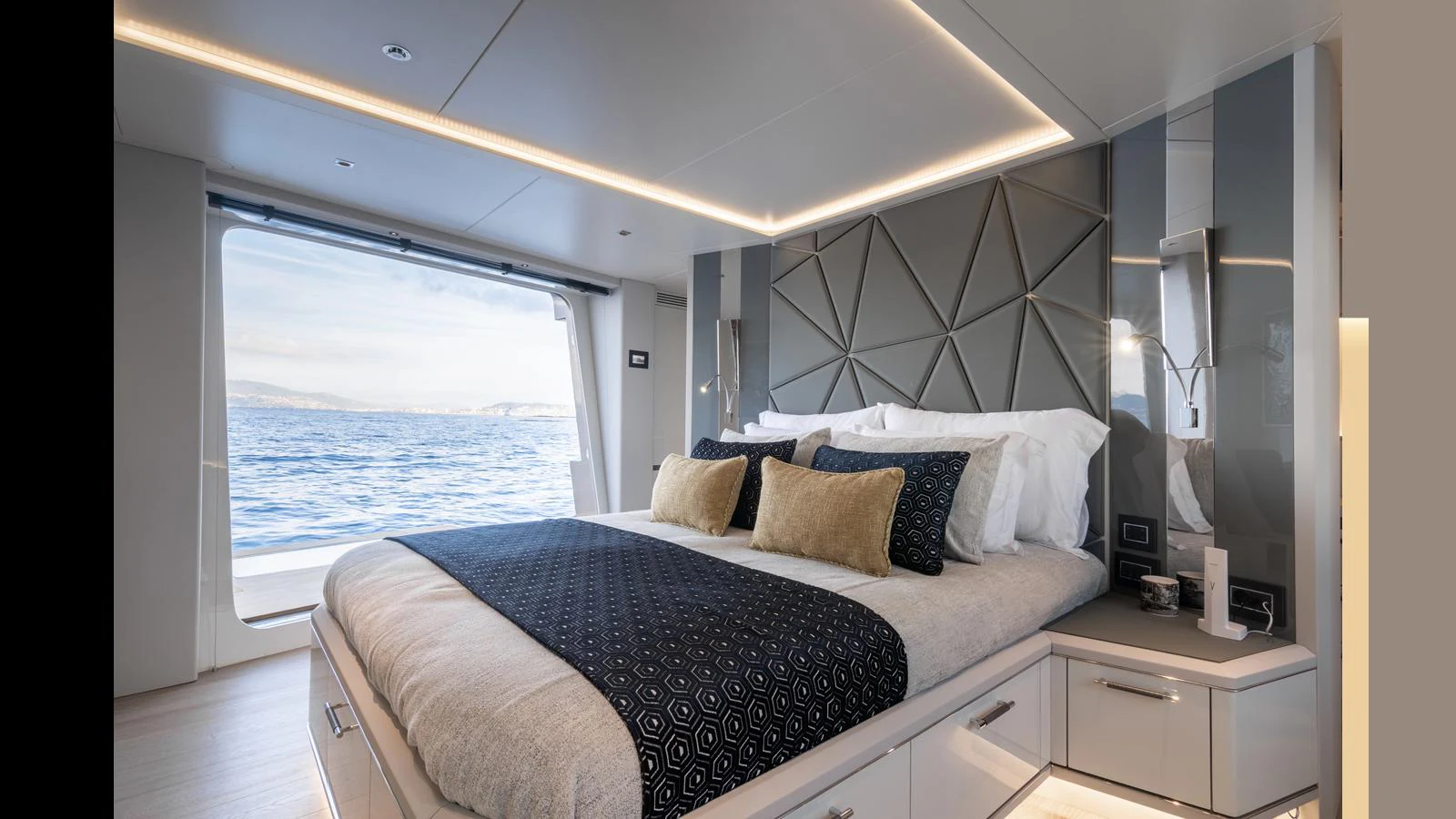 A luxurious stateroom with a large bed and a stunning ocean view through a sliding door. aboard HULL #5 Yacht for Sale