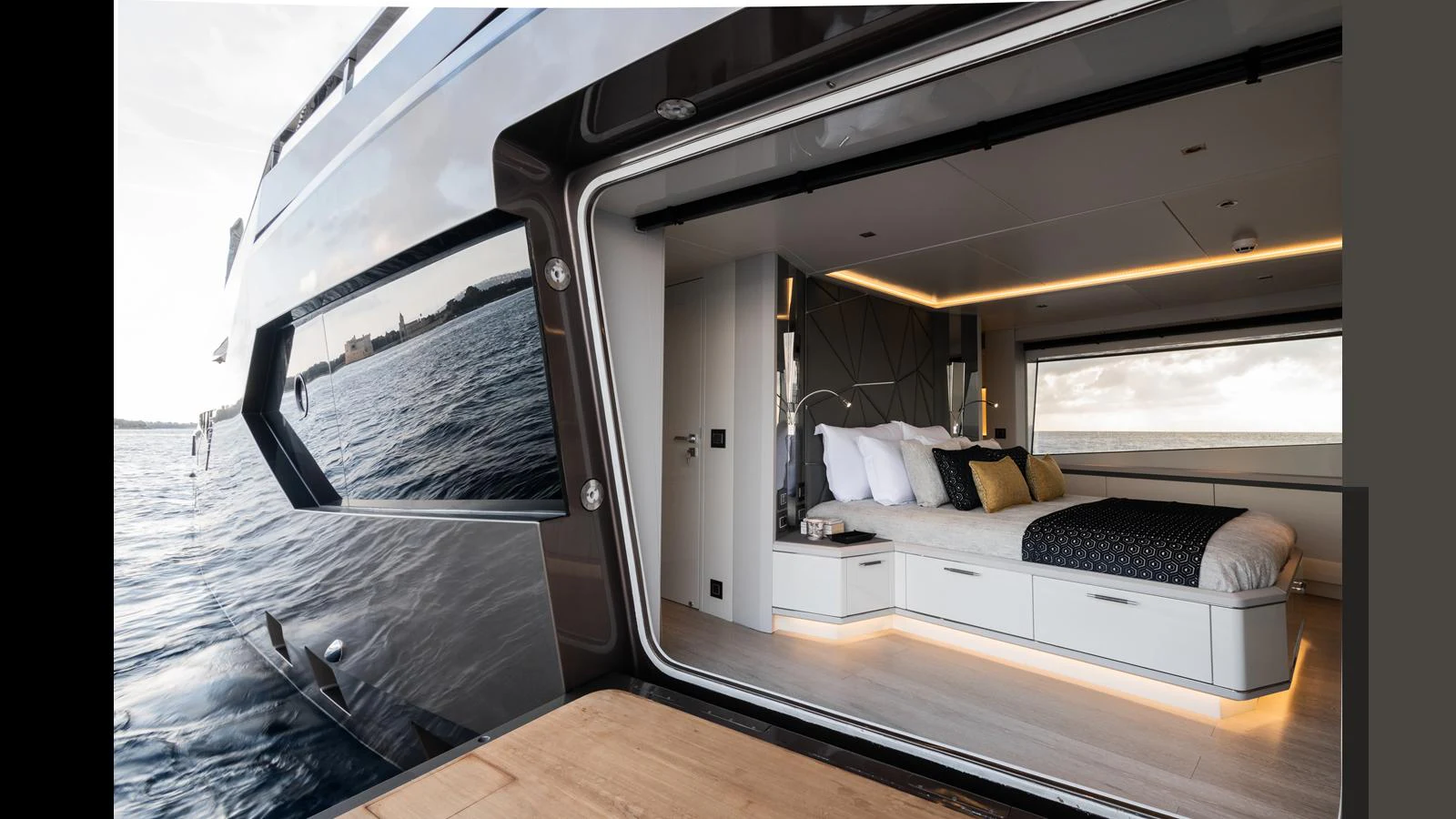 A luxurious stateroom with a large bed and modern design, opening to a view of the water. aboard HULL #5 Yacht for Sale