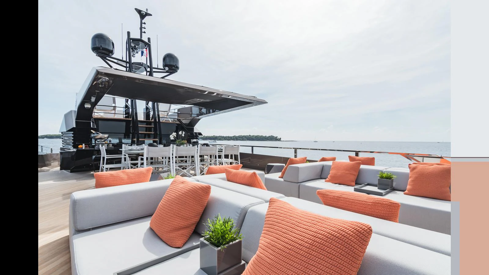 The sundeck offers a luxurious outdoor lounging area with plush seating and vibrant orange cushions, perfect for relaxation and socializing. aboard HULL #5 Yacht for Sale