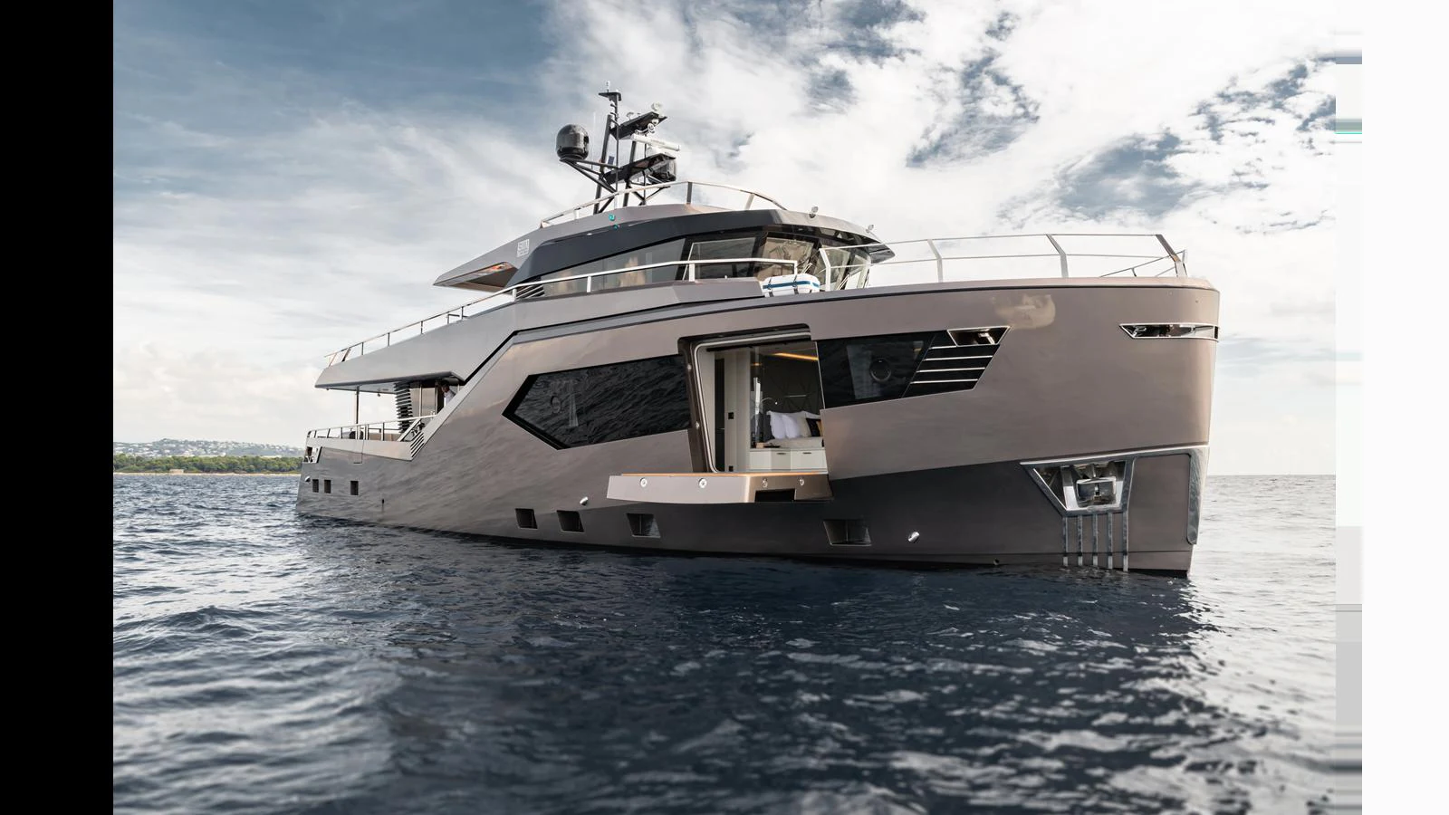 A sleek and modern yacht cruising on calm waters under a partly cloudy sky. aboard HULL #5 Yacht for Sale