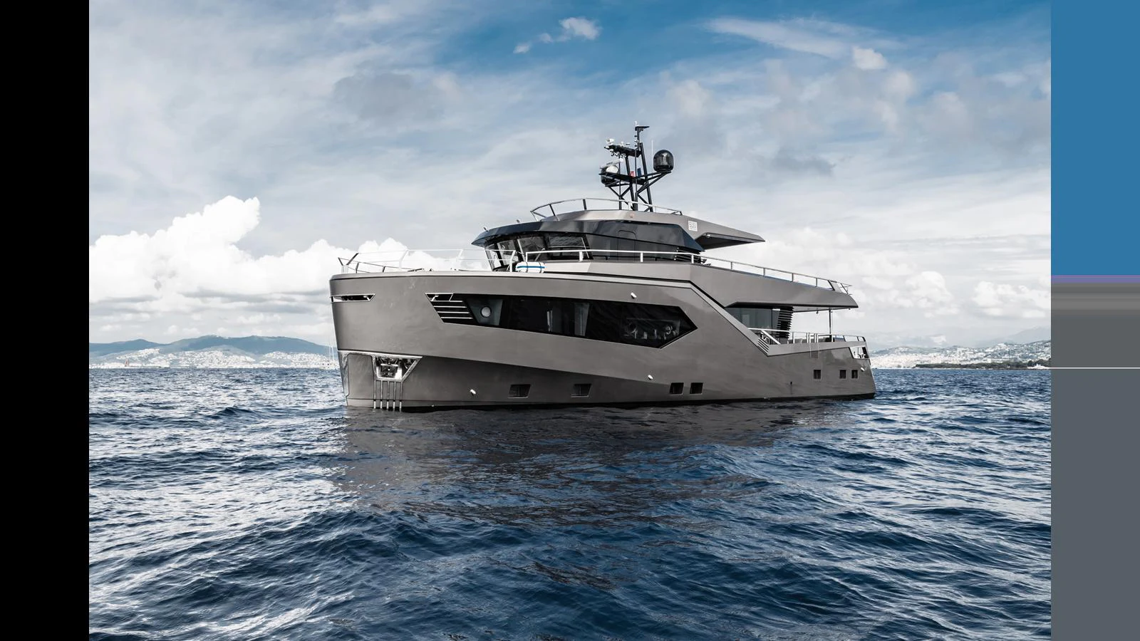 A sleek and modern yacht cruises on open waters under a partly cloudy sky. aboard HULL #5 Yacht for Sale