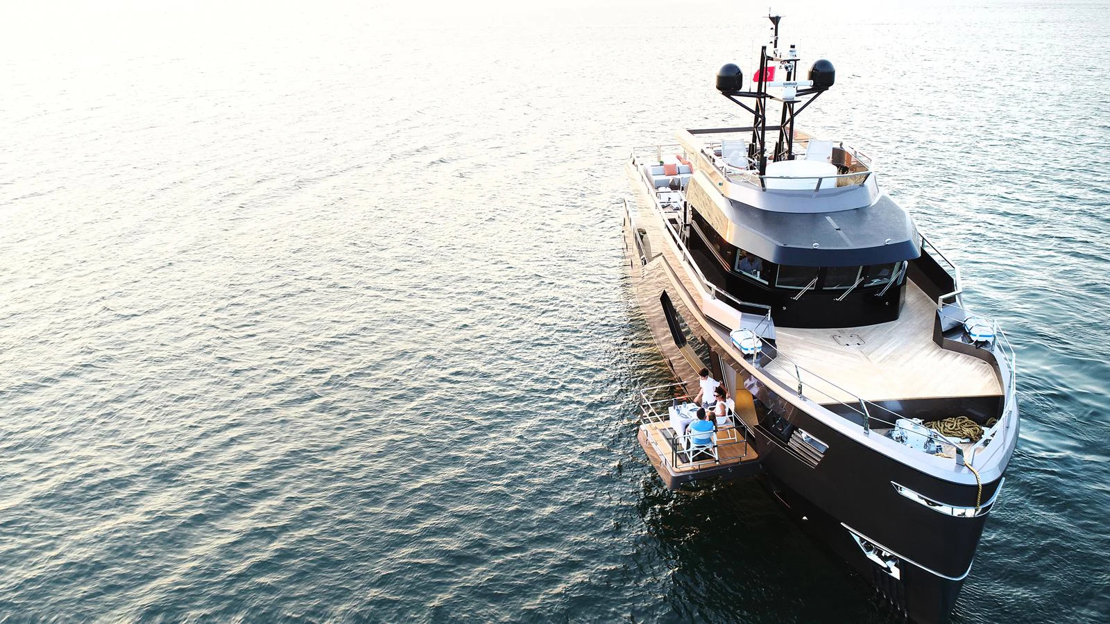 A sleek yacht is anchored on calm waters, showcasing its modern design and spacious deck. aboard HULL #5 Yacht for Sale