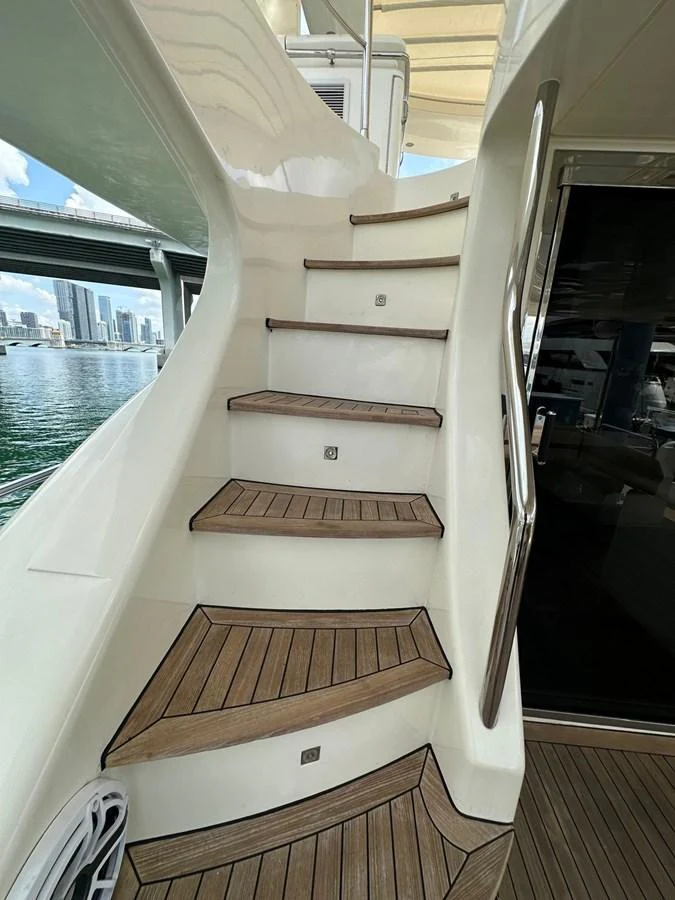 Elegant wooden steps lead up to the upper deck, showcasing the yacht's craftsmanship. aboard 75FT AZIMUT 2010, MINIMAL RISK Yacht for Sale
