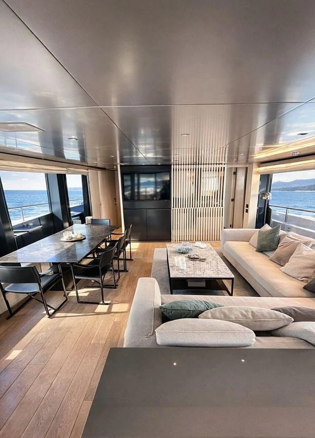 The salon features a modern and spacious design with ample seating and a dining area, offering panoramic views through large windows. aboard SAAM II Yacht for Sale