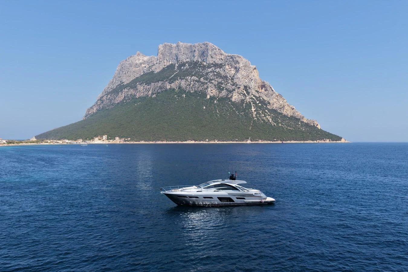A sleek yacht cruises in front of a majestic mountainous backdrop on a clear day. aboard VENTUS 1 Yacht for Sale