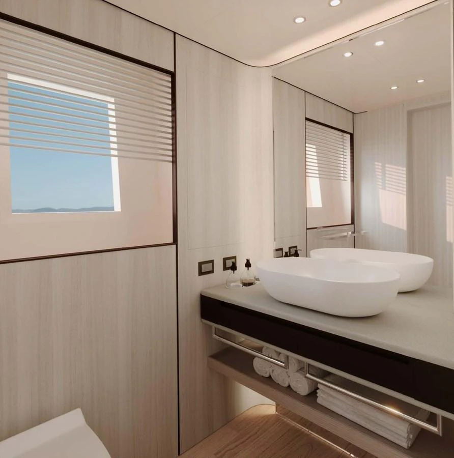 A modern yacht bathroom featuring dual sinks and a large mirror, with natural light streaming in through the window. aboard LUMINA Yacht for Sale