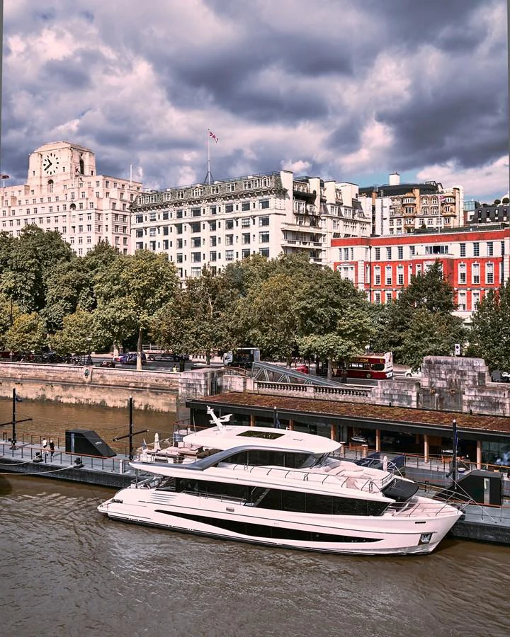 A sleek yacht is docked along a bustling city waterfront, showcasing its modern design against an urban backdrop. aboard PRINCESS X90 Yacht for Sale
