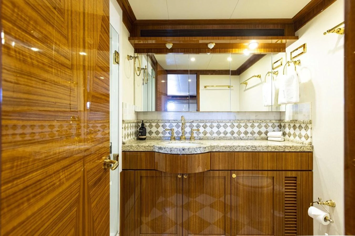 The yacht's bathroom features elegant wood paneling and a granite countertop with a large mirror. aboard ODYSSEY Yacht for Sale