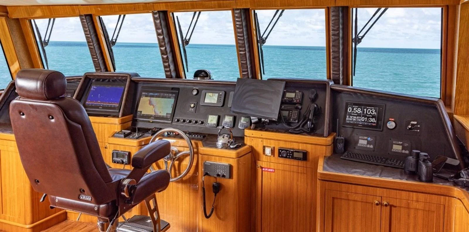 The helm station features advanced navigation equipment and a comfortable captain's chair, all set against a backdrop of expansive ocean views. aboard ODYSSEY Yacht for Sale