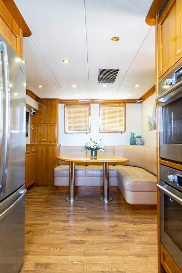 The galley features a cozy dining nook with a wooden table and comfortable seating. aboard ODYSSEY Yacht for Sale
