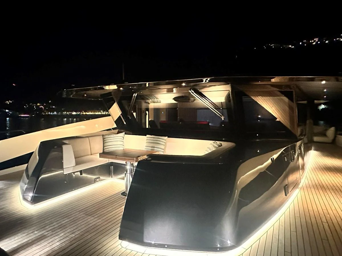 The yacht's aft deck is elegantly illuminated at night, showcasing a sleek design and comfortable seating area. aboard ATALI Yacht for Sale
