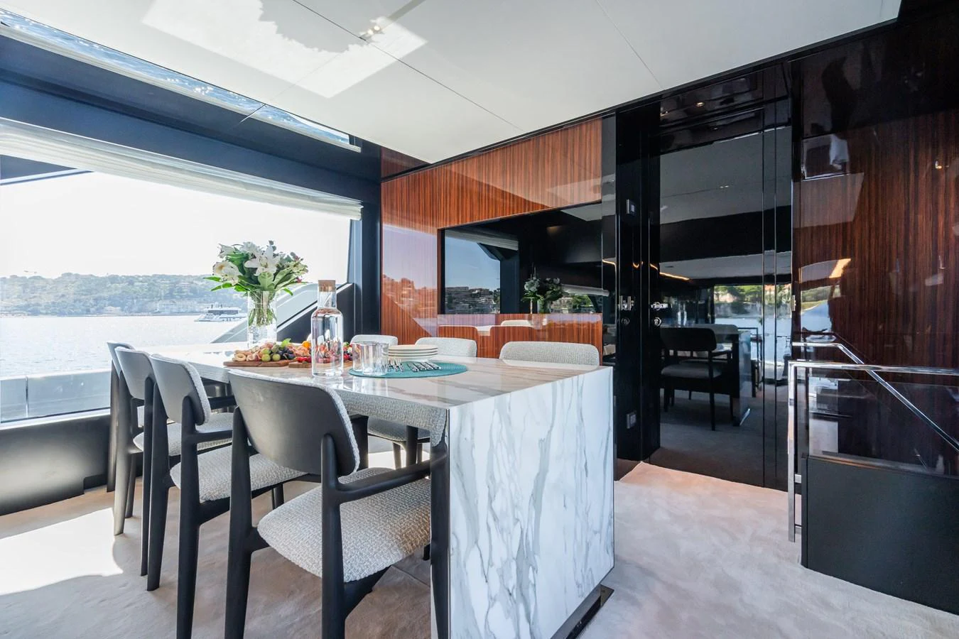 The yacht's dining area features a sleek marble table and modern chairs, with large windows offering stunning views. aboard L'AS BLEU Yacht for Sale