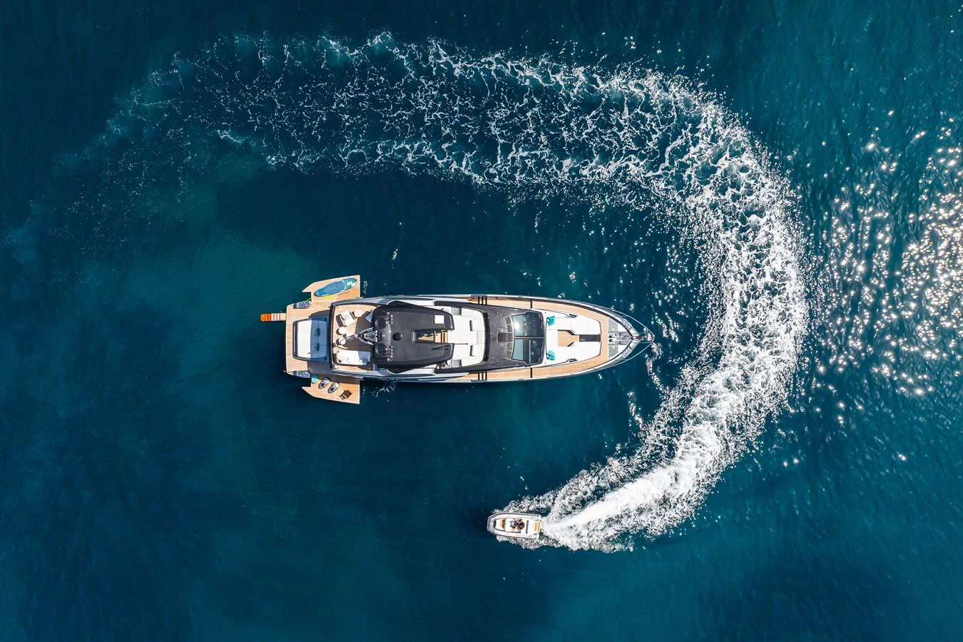 An aerial view of a luxurious yacht cruising through clear blue waters, leaving a trail of white wake. aboard L'AS BLEU Yacht for Sale