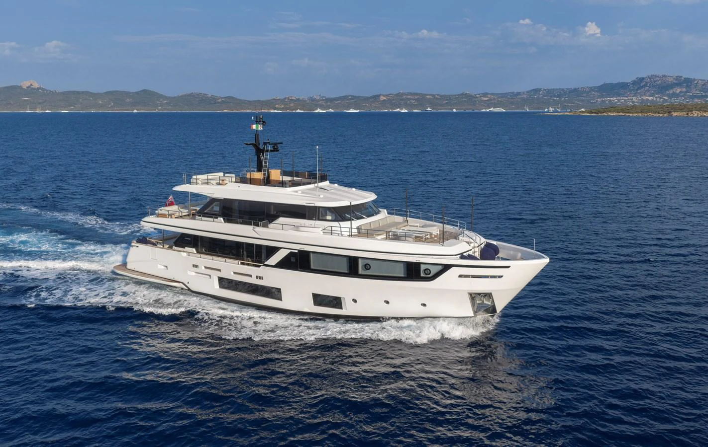 A sleek and modern yacht cruises through calm blue waters with a scenic coastline in the background. aboard CLAIRE DE LUNE Yacht for Sale
