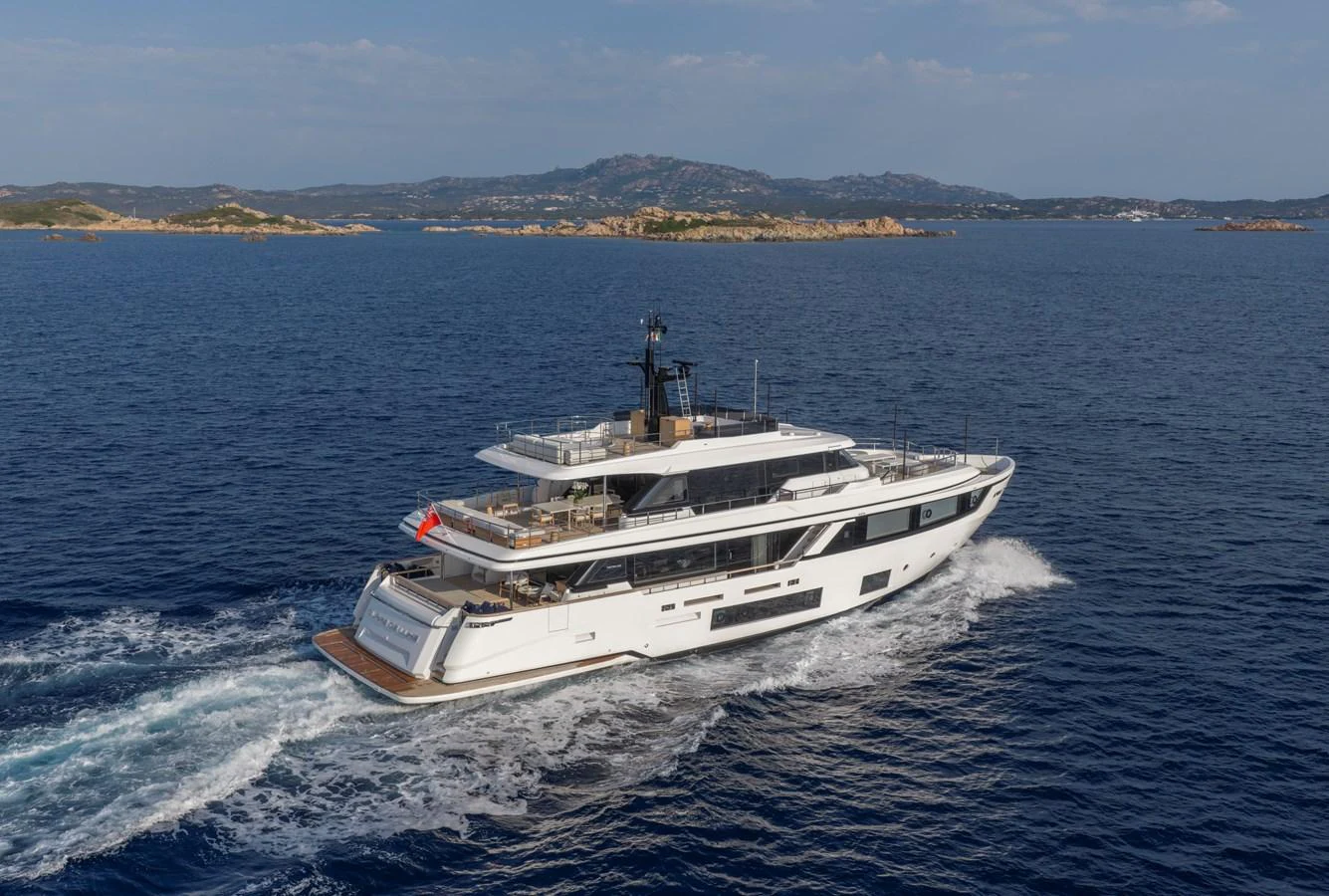A sleek yacht cruises through calm blue waters with scenic hills in the background. aboard CLAIRE DE LUNE Yacht for Sale