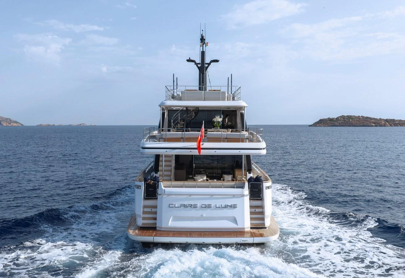 The yacht is seen cruising on open waters, showcasing its sleek and modern design from the rear. aboard CLAIRE DE LUNE Yacht for Sale