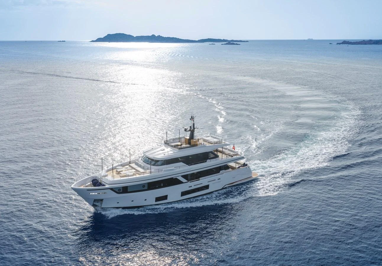 A luxurious yacht cruises gracefully through calm, open waters with a scenic island in the background. aboard CLAIRE DE LUNE Yacht for Sale