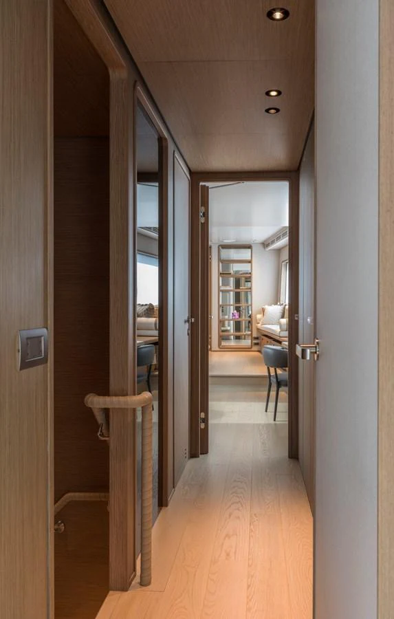 A sleek hallway with wooden finishes leads to a cozy seating area. aboard CLAIRE DE LUNE Yacht for Sale