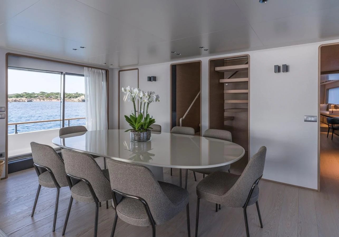 The yacht's dining area features a sleek, modern table with comfortable seating and a view of the water through large windows. aboard CLAIRE DE LUNE Yacht for Sale