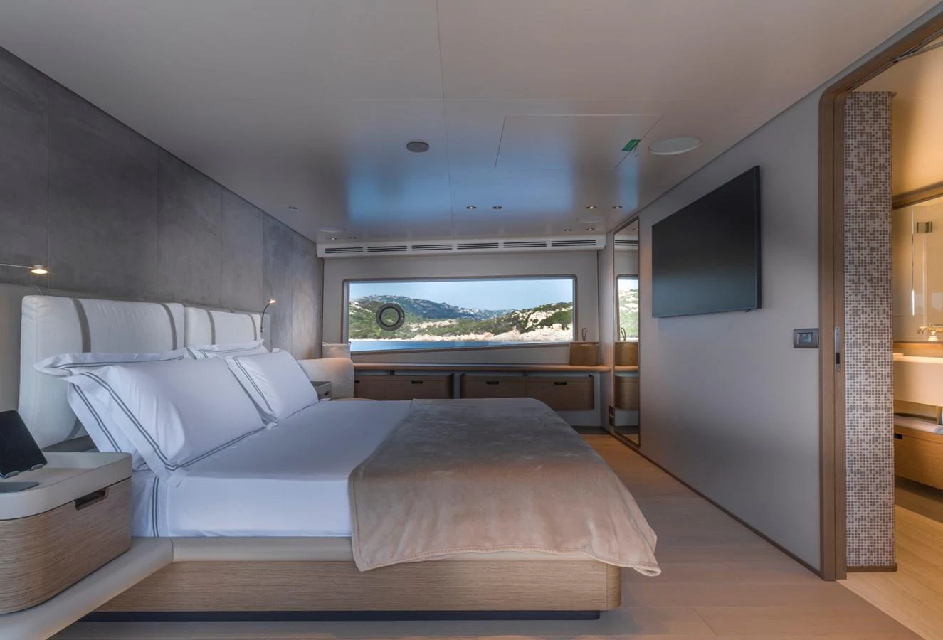 A luxurious stateroom featuring a large bed, modern furnishings, and a scenic view through a wide window. aboard CLAIRE DE LUNE Yacht for Sale