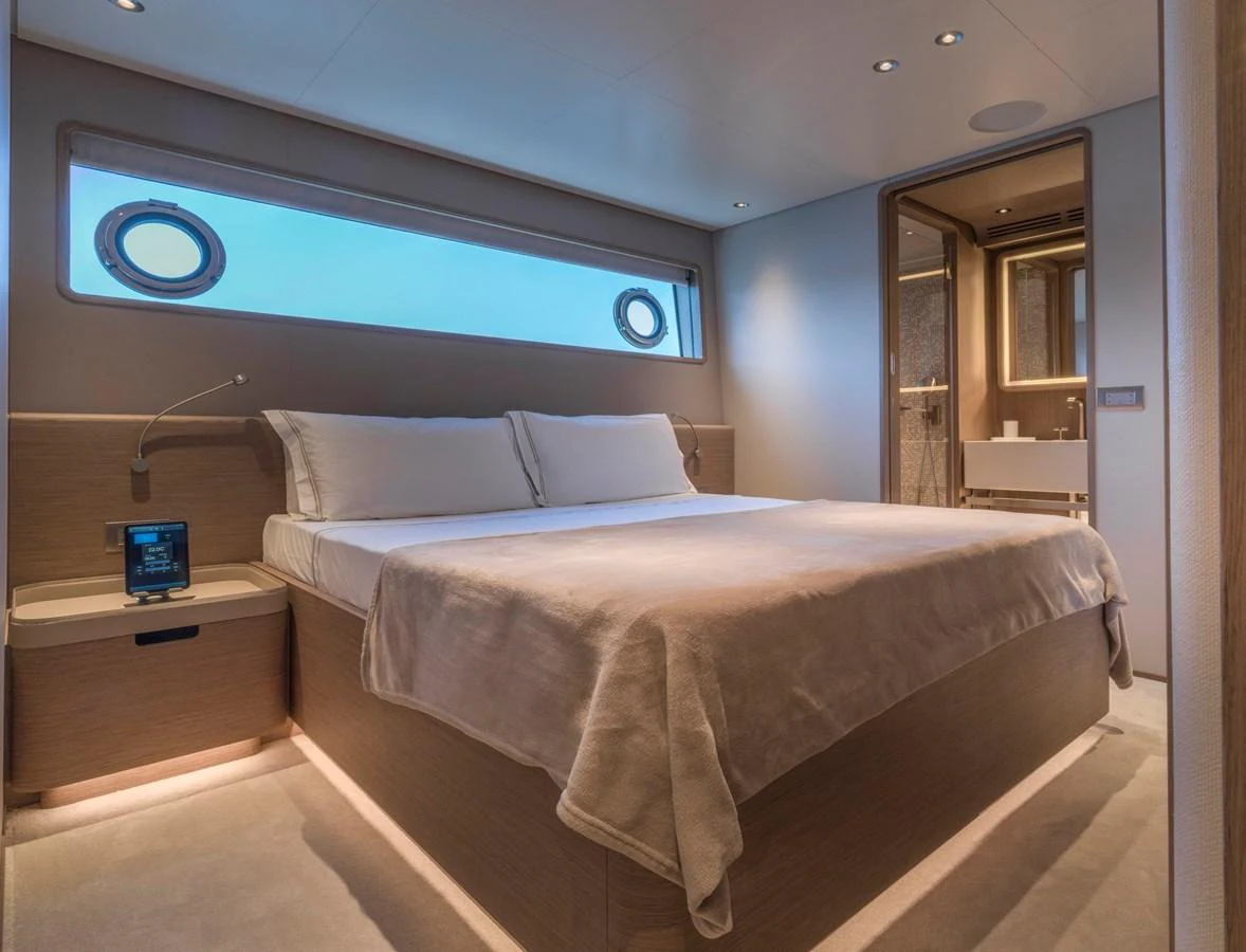 The stateroom features a luxurious bed with modern lighting and a view of the sea through the porthole windows. aboard CLAIRE DE LUNE Yacht for Sale