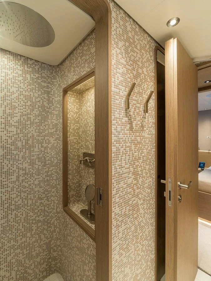 A modern yacht bathroom with mosaic tile walls and wooden accents. aboard CLAIRE DE LUNE Yacht for Sale