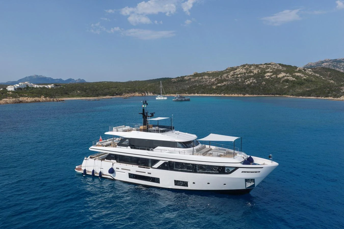 A luxurious yacht cruises through pristine blue waters with a scenic coastal backdrop. aboard CLAIRE DE LUNE Yacht for Sale