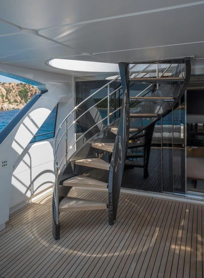 A sleek spiral staircase connects the yacht's decks, framed by elegant glass and stainless steel accents. aboard CLAIRE DE LUNE Yacht for Sale