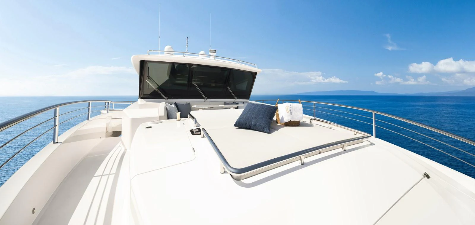 The yacht's foredeck offers a spacious sunbathing area with plush cushions and stunning ocean views. aboard HORIZON FD80/19 Yacht for Sale