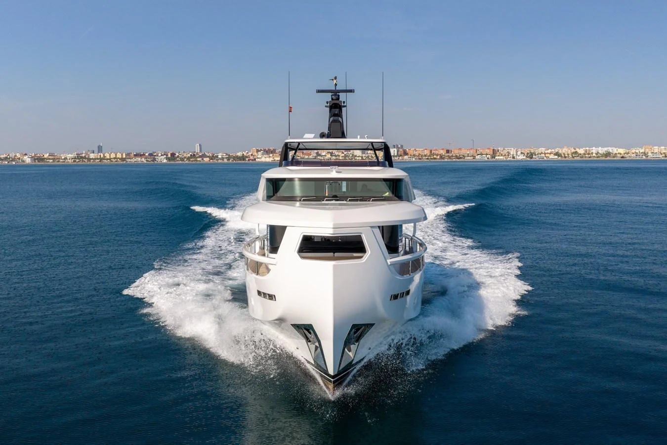 A sleek yacht cuts through the water, showcasing its modern design against a coastal backdrop. aboard SEA SAKURA Yacht for Sale