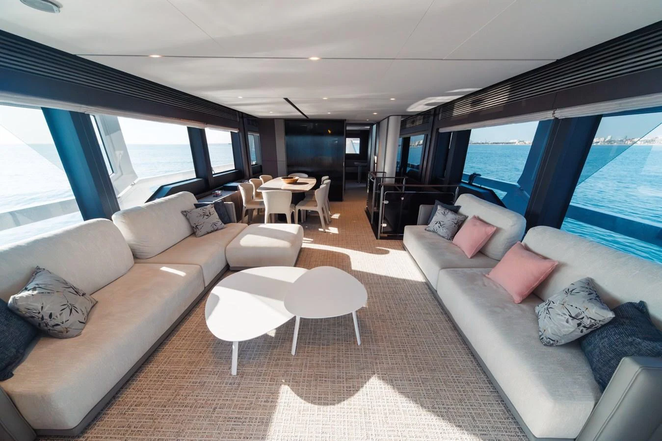 The salon features plush seating with panoramic windows offering stunning ocean views. aboard SEA SAKURA Yacht for Sale