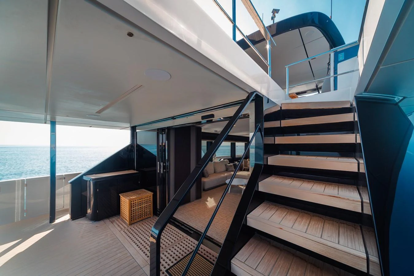 The aft deck features a stylish staircase leading to the upper deck, with a comfortable seating area and a view of the sea. aboard SEA SAKURA Yacht for Sale