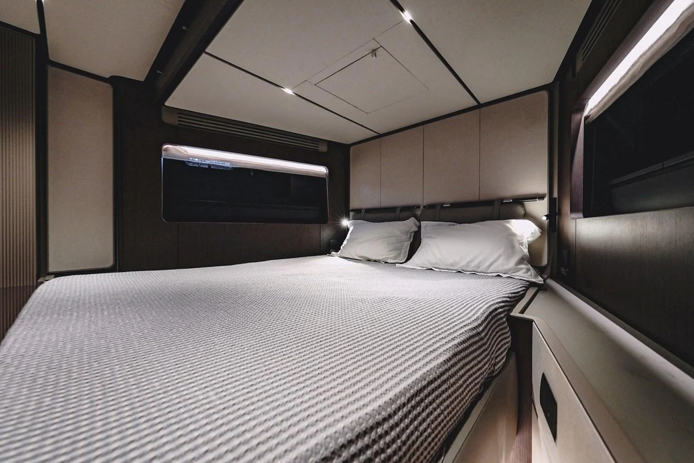 The stateroom features a comfortable bed with modern lighting and sleek design. aboard SEA SAKURA Yacht for Sale