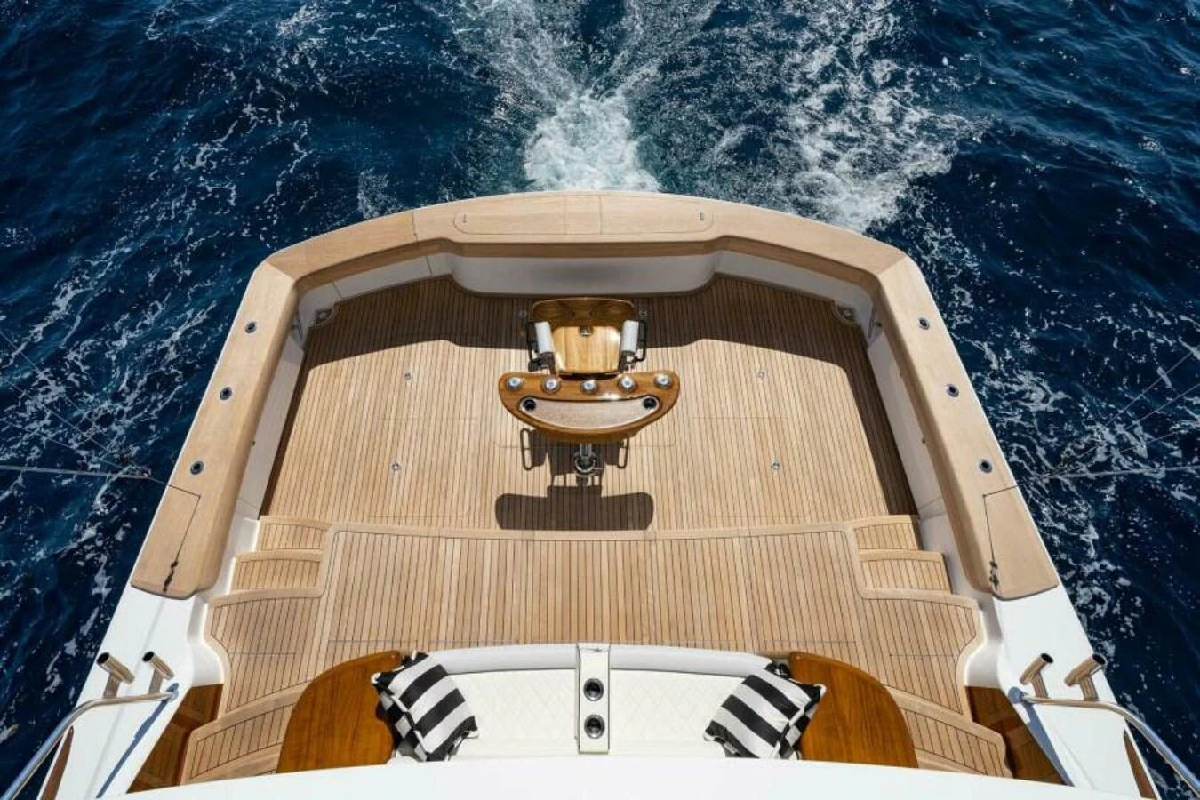 The aft deck features a spacious teak layout with a central fighting chair, perfect for sportfishing adventures. aboard 2027 VIKING 90SB Yacht for Sale
