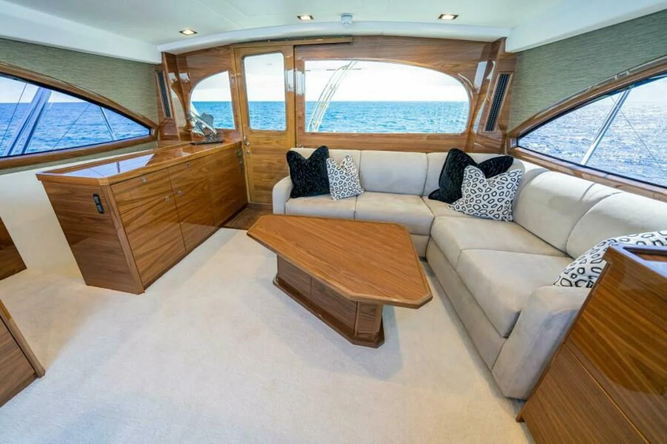 The salon features a comfortable seating area with elegant wood finishes and large windows offering a view of the sea. aboard 2027 VIKING 90SB Yacht for Sale